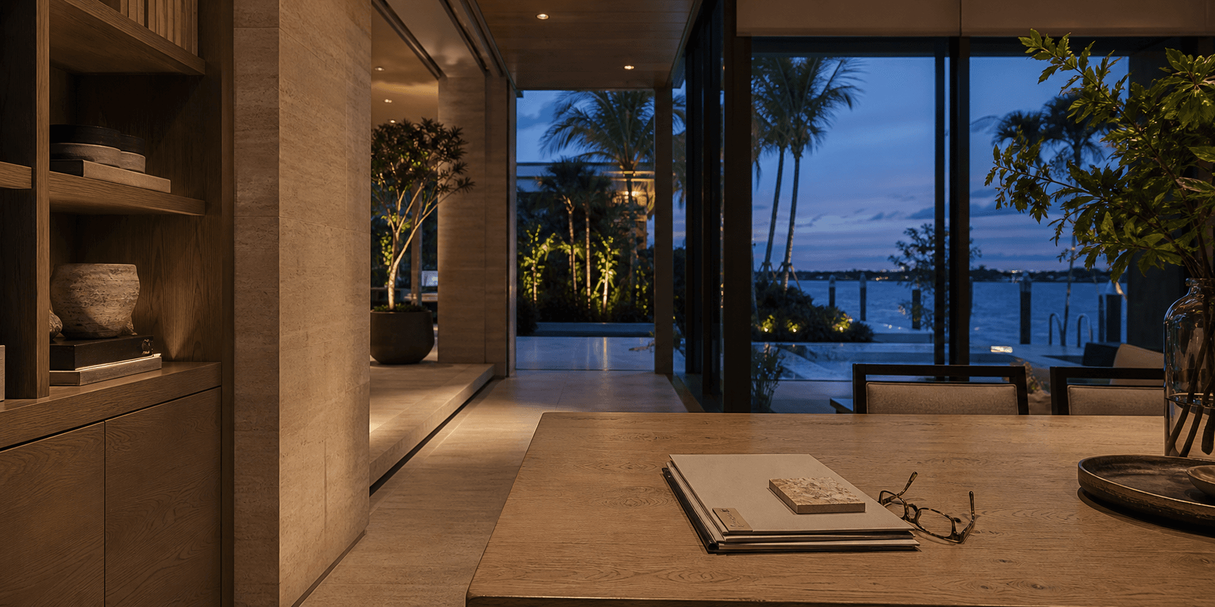 Orderly property documents and reading glasses in a warm South Florida waterfront residence at dusk